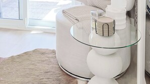 A modern living room with a glass coffee table, a beige sofa, and a view through a sliding glass door.