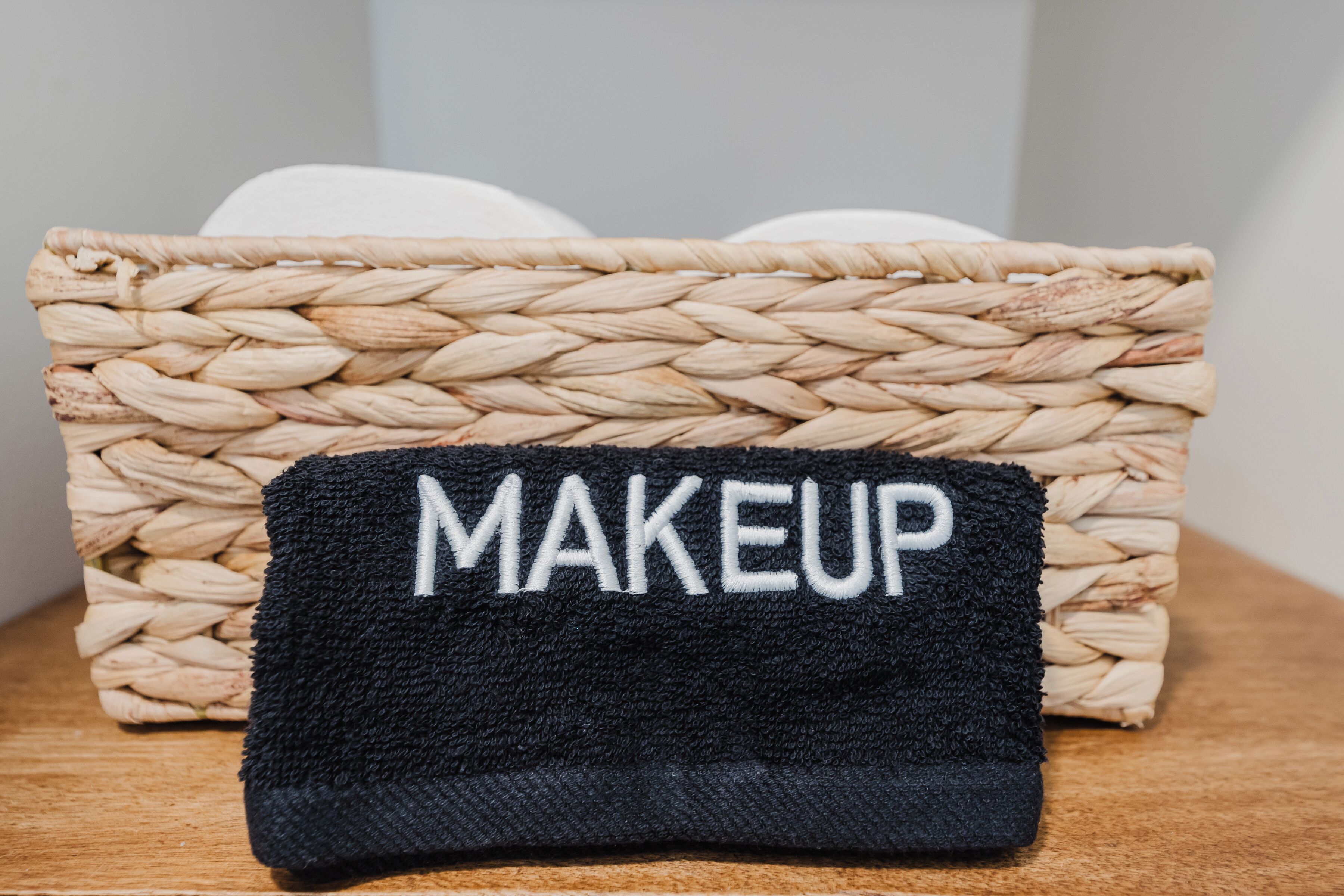 A woven basket with a black cloth labeled 'MAKEUP' on a wooden surface.