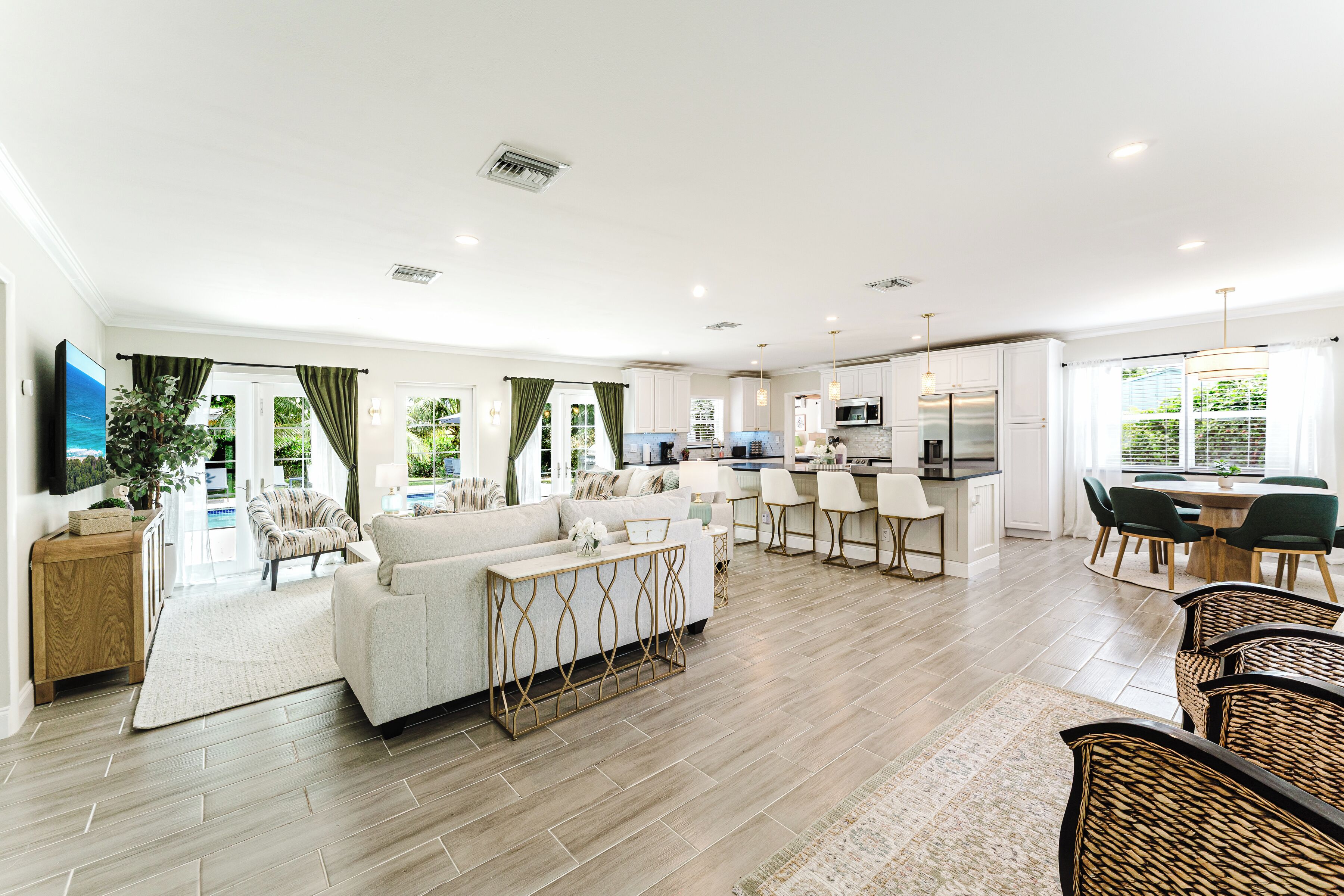 A spacious living area with a sofa, dining table, and chairs, a kitchen with modern appliances, and a view of the outdoors.