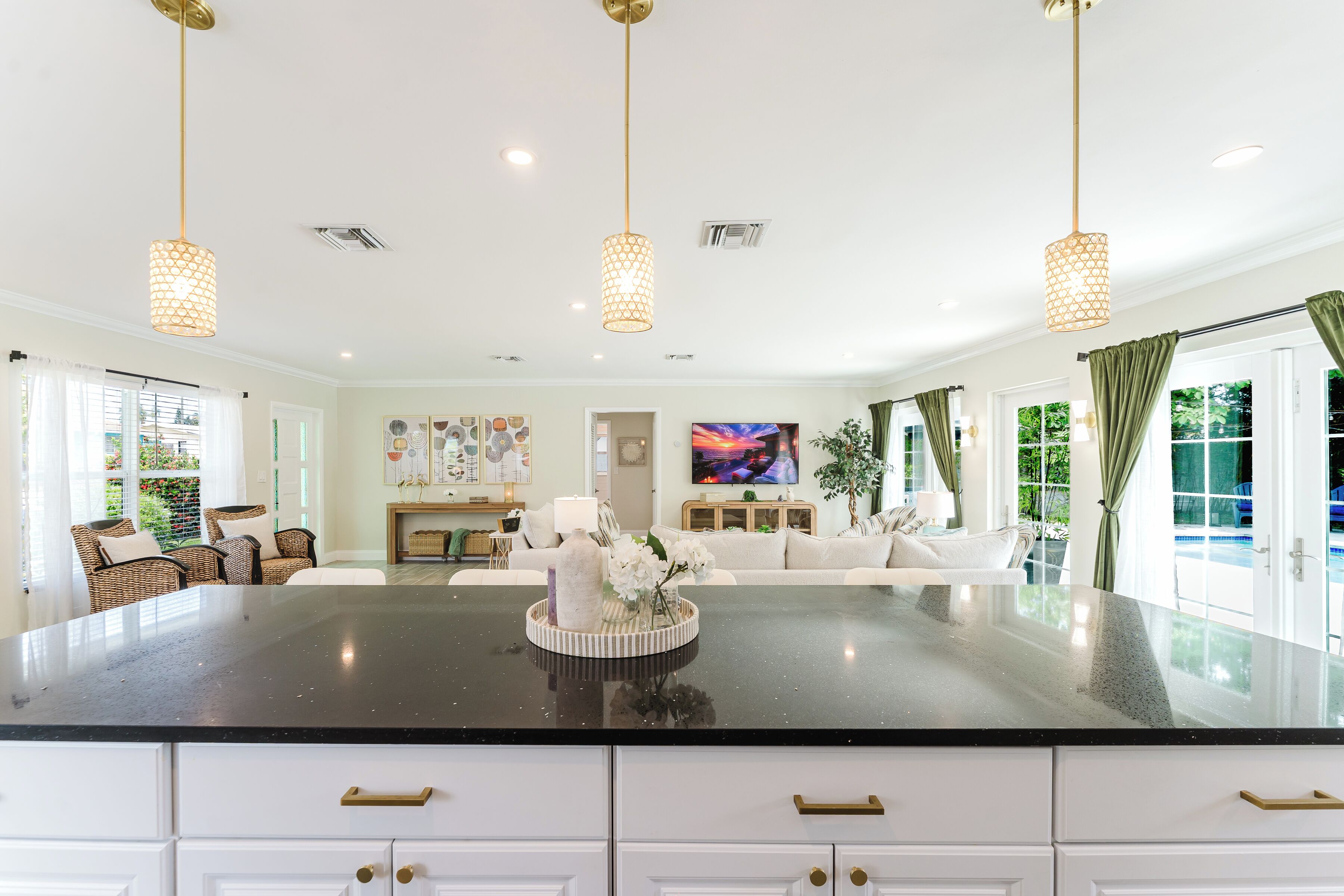 A spacious living room with a large island, white cabinetry, and a television.