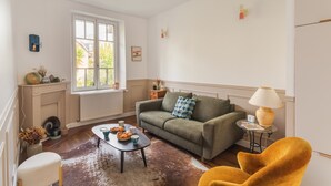 Uma sala de estar com sofá, mesa de centro, abajur e lareira.