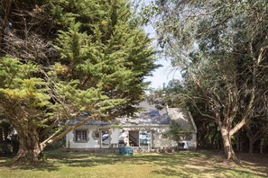 A house with a covered porch, surrounded by trees. - Chez Mab - Maison familiale les pieds dans l'eau (Saint-Armel)