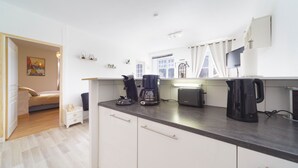 A modern kitchen with white cabinets, a coffee maker, and a kettle on the counter. - Le Gîte de Pount d'Iher - Proche GR10 (Laruns)