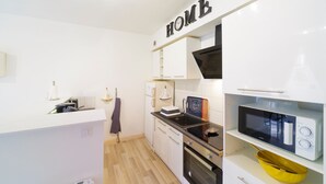 A modern kitchen with white cabinetry, a microwave, an oven, and a sink. - Le Gîte de Pount d'Iher - Proche GR10 (Laruns)