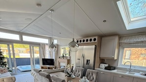A modern kitchen with a dining area, a TV, and a large window. - Host Stay The White Swan (York)