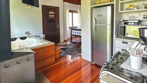 A modern kitchen with wooden beams, a stainless steel refrigerator, a gas stove, and a dining area with a view. - Morada Das Grimpas (Palmeira)