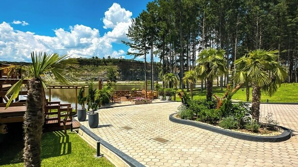 A paved patio area with a seating arrangement, surrounded by greenery and trees. - Morada Das Grimpas (Palmeira)