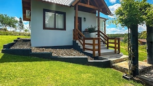 A two-story house with a tiled roof, a wooden porch, and a well-maintained lawn. - Morada Das Grimpas (Palmeira)
