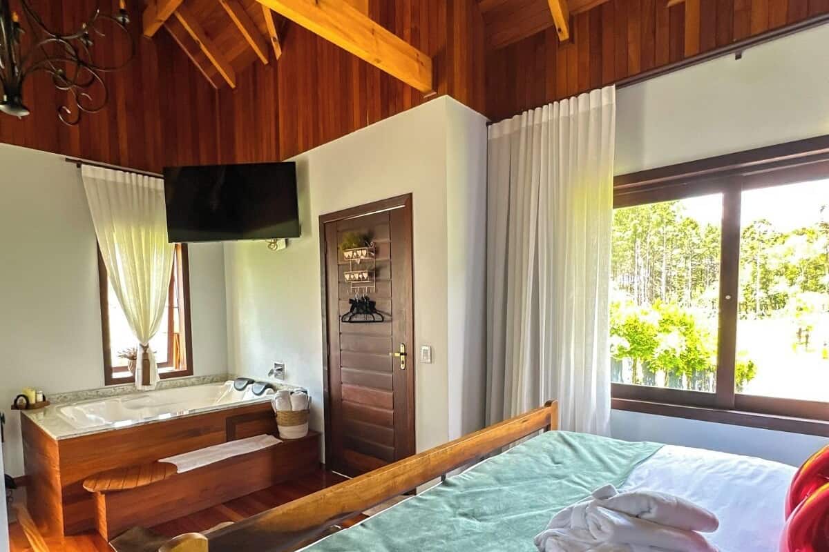 A wooden cabin-style room with a bed, a bench, a sink, and a TV.