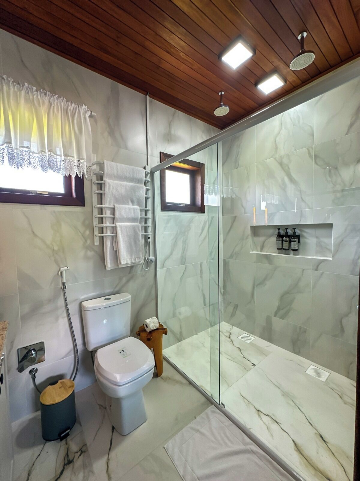 A modern bathroom with a glass shower enclosure, a toilet, and a sink.