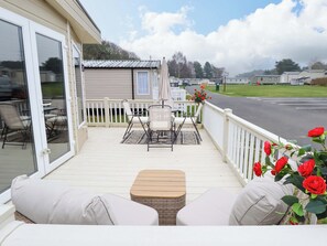 A covered outdoor area with a seating arrangement, a table, and a view of the street. - 108 Fox Burrow Hang (Great Yarmouth)