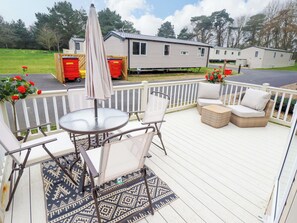 A deck with outdoor furniture, a table, and an umbrella. - 108 Fox Burrow Hang (Great Yarmouth)