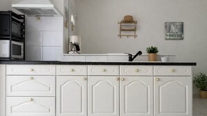 Cucina con mobili bianchi, piano di lavoro nero e cappa in acciaio inossidabile.