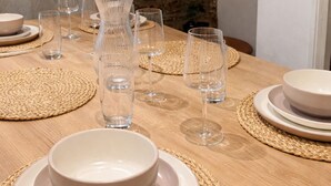 A dining table set with plates, bowls, and glasses, with a stone wall in the background. - Home in Hotwells (Bristol)