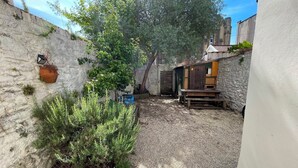 A narrow courtyard with a gravel path, a wooden bench, and a potted plant. - Home in Hotwells (Bristol)