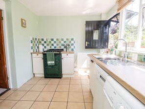 A compact kitchen with a stove, sink, and tiled backsplash. - Yewbarrow (Seascale)
