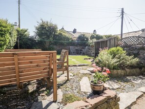 A wooden bench, a potted plant, and a stone wall in a garden setting. - Yewbarrow (Seascale)