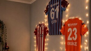 A room with three sports jerseys hanging on the wall, a round glass table with chairs, and fairy lights. - las vegas (Batumi)