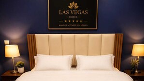 A hotel room with a bed, two bedside lamps, a wall sign, and a wooden headboard. - las vegas (Batumi)