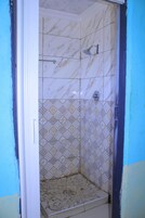 Una ducha con pared de azulejos estampados, un cabezal de ducha y desagüe.