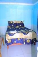 Una cama con ropa de cama floral, un cabecero de madera y un piso de baldosas.