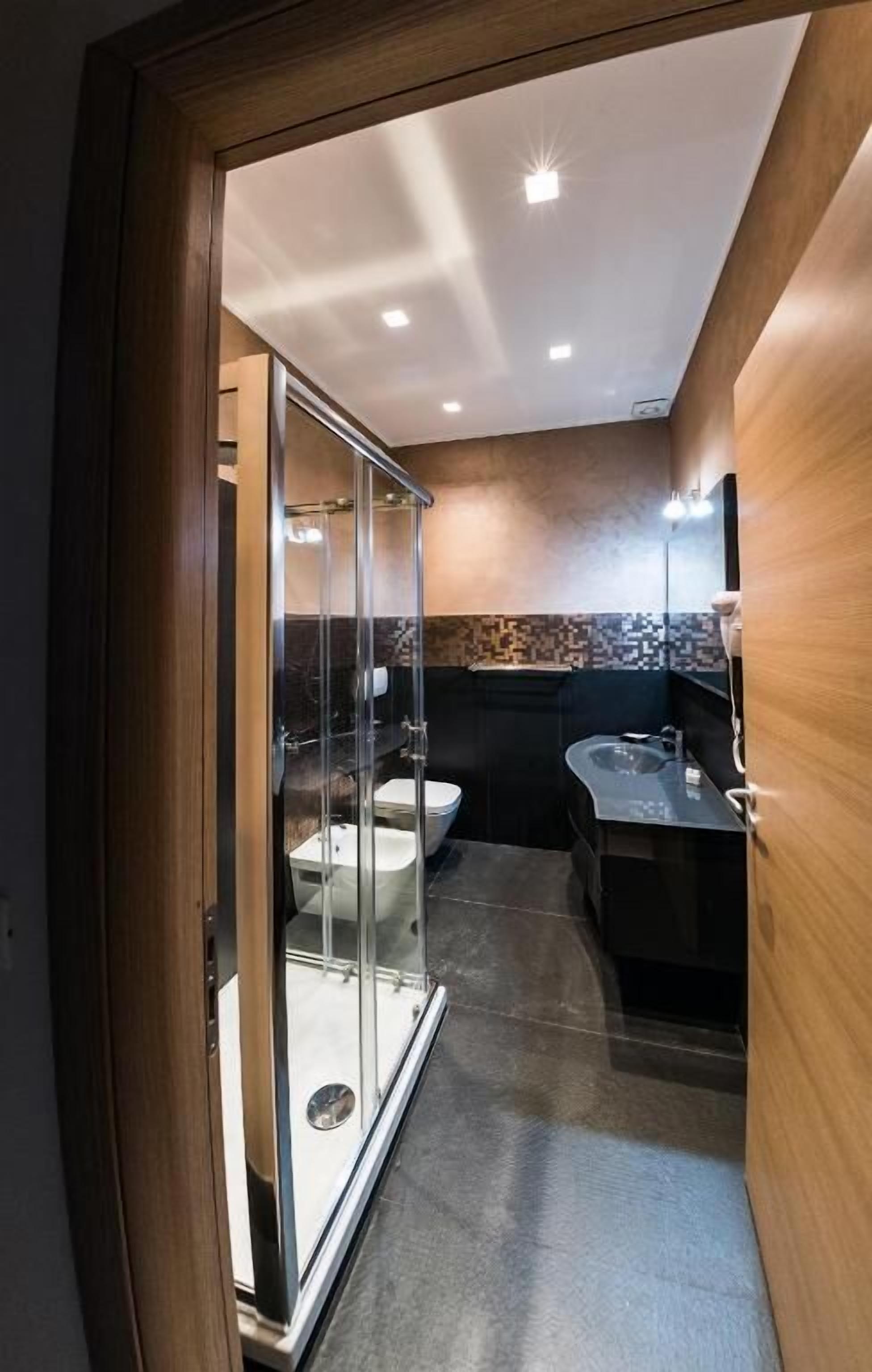 A modern bathroom with a glass shower enclosure, a separate sink area, and a vanity with a mirror.