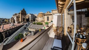 A balcony with a view of historic buildings, a street, and a clear sky. - Aristonsuite (Piazza Armerina)