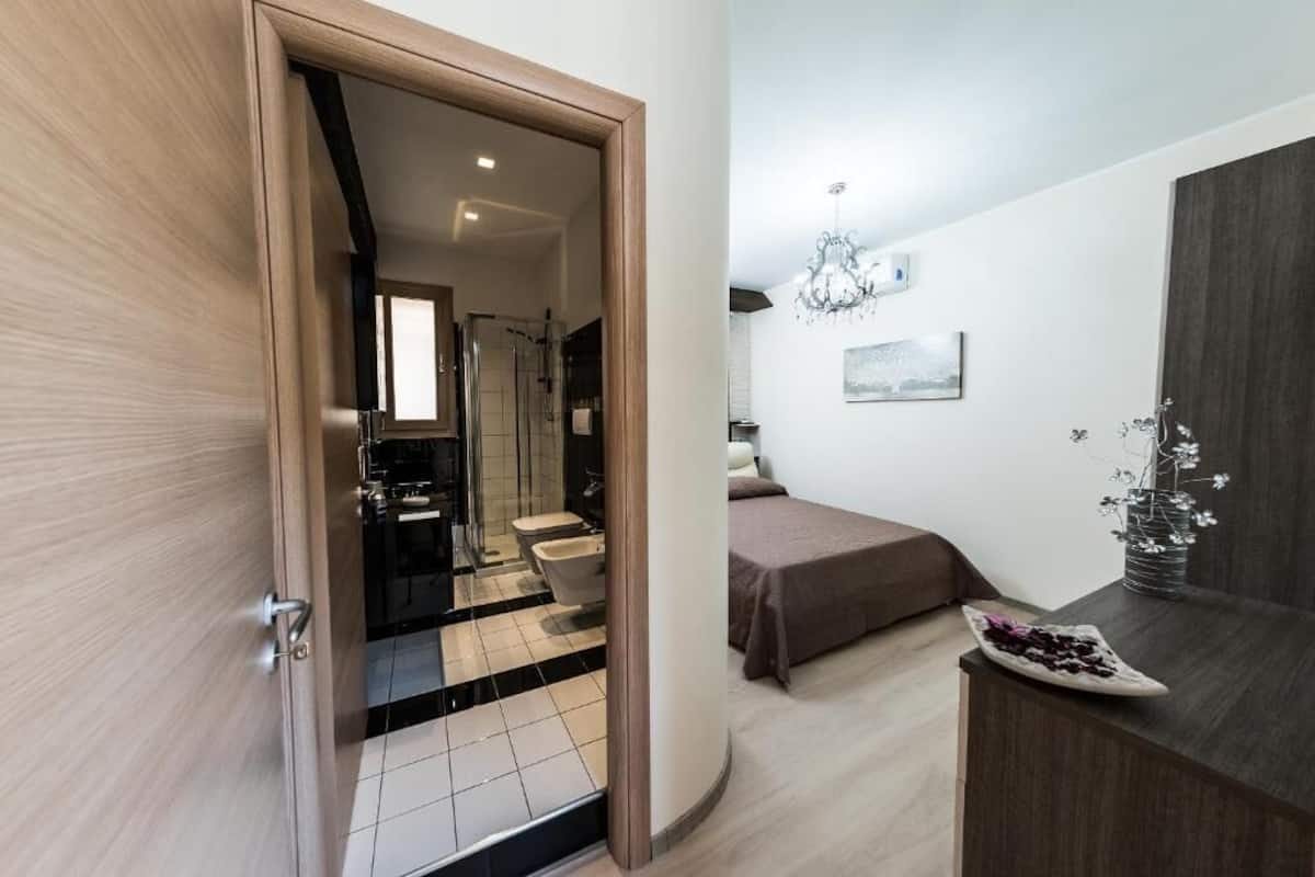 Un dormitorio moderno con cama, mesita de noche y vistas al baño.