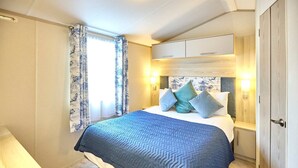 Ein Schlafzimmer mit Bett, Nachttischen, einem Kleiderschrank und einem Fenster mit Vorhängen.