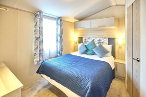 A bedroom with a bed, bedside tables, a wardrobe, and a window with curtains. - Host Stay Cedar Lodge (York)