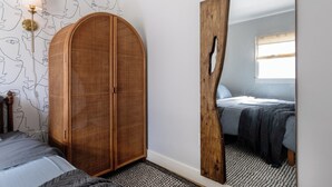 A bedroom with a large mirror, a wardrobe, a bed with a patterned bedspread, and a wall with a line drawing design. - 2BR Cozy Home Serene Garden Retreat Near UC Berkeley San Francisco (Richmond)