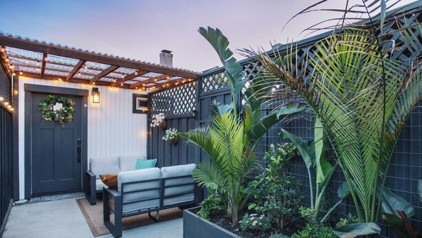 A patio with a grey bench, a decorative wreath on the door, and a garden with various plants. - 2BR Cozy Home Serene Garden Retreat Near UC Berkeley San Francisco (Richmond)