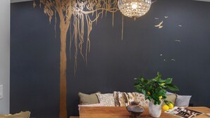 A dining area with a wooden table, a chandelier, a wall mural, and a potted plant. - 2BR Cozy Home Serene Garden Retreat Near UC Berkeley San Francisco (Richmond)