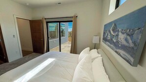 A hotel room with a large bed, a painting on the wall, and a view through the door. - The Overlook on Mountain View (Lead)