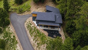 A modern house with a curved driveway, surrounded by dense forest. - The Overlook on Mountain View (Lead)