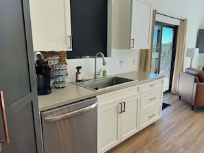 A modern kitchen with a stainless steel refrigerator, a sink, and a coffee machine. - The Overlook on Mountain View (Lead)