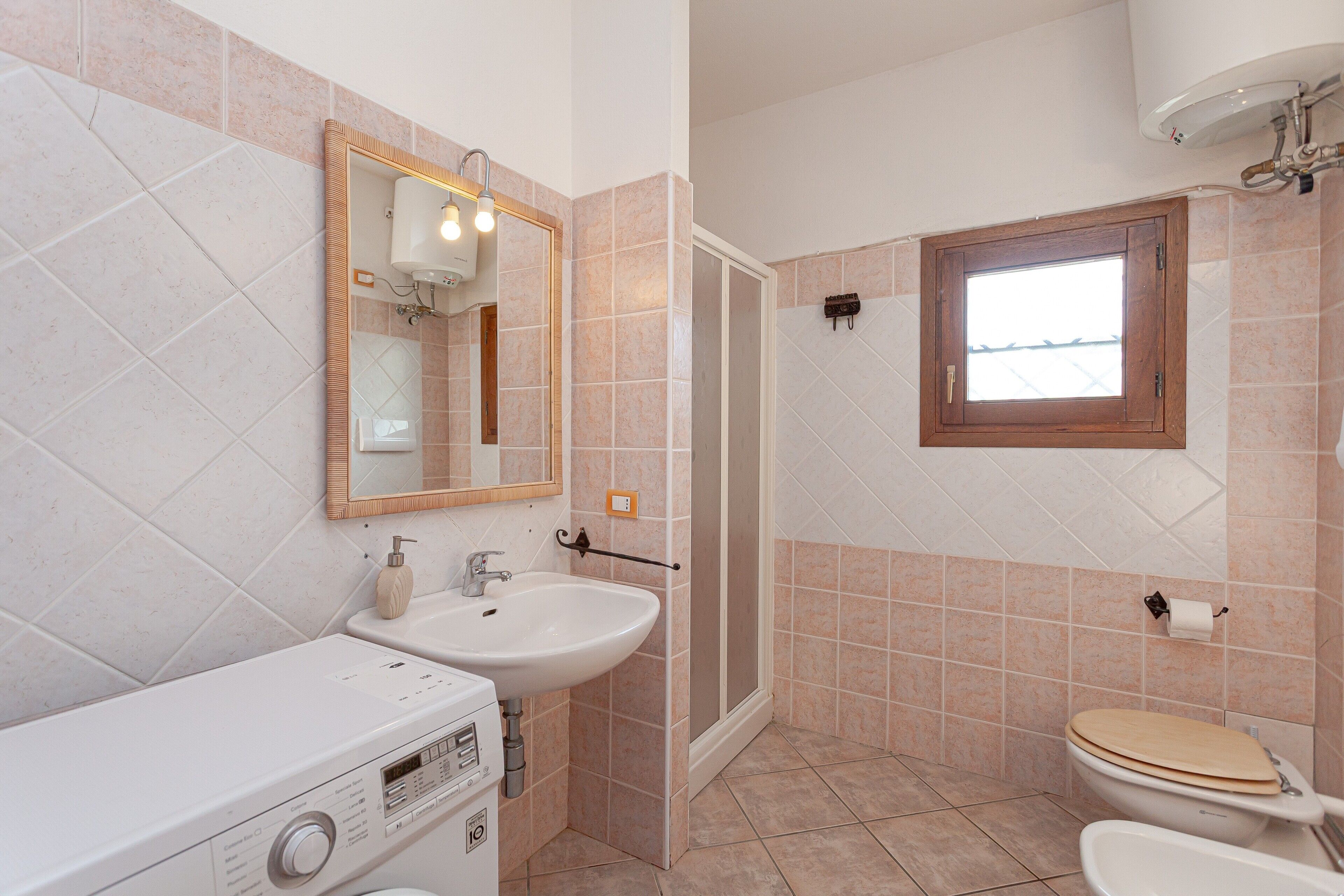 Une salle de bain équipée d’un lavabo, d’un miroir, de toilettes, d’une douche et d’une fenêtre.