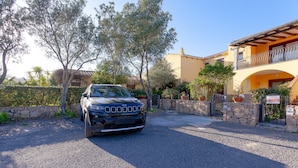 A black SUV parked in front of a building with a stone wall, a balcony, and potted plants. - Holiday Home 'San Teodoro House with Garden' with Mountain View, Wi-Fi and Air Conditioning (Suaredda-traversa)