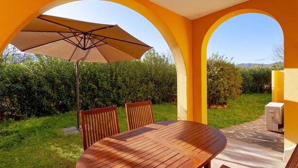 An outdoor patio with a wooden table and chairs, an umbrella, and a view of a garden and hills. - Holiday Home 'San Teodoro House with Garden' with Mountain View, Wi-Fi and Air Conditioning (Suaredda-traversa)
