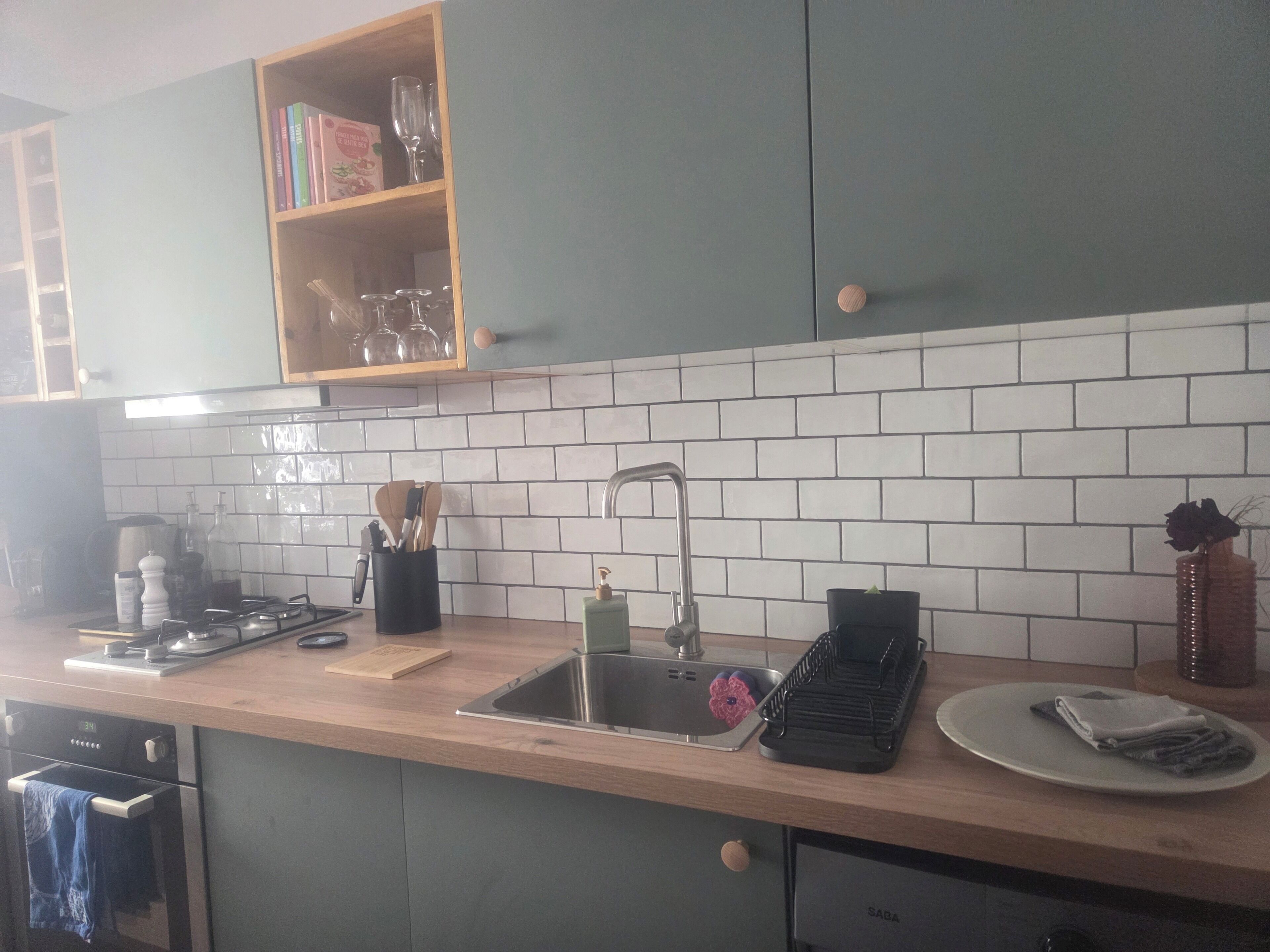 Una cocina con encimera de madera, pileta de acero inoxidable, escurreplatos y lavavajillas SABA.