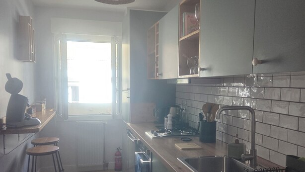 A kitchen with a wooden countertop, a hanging light fixture, a window, and a fire extinguisher.