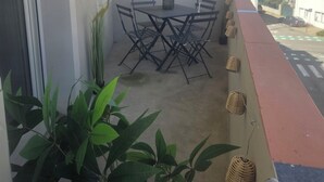 A balcony with a table and chairs, potted plants, and a view of buildings.