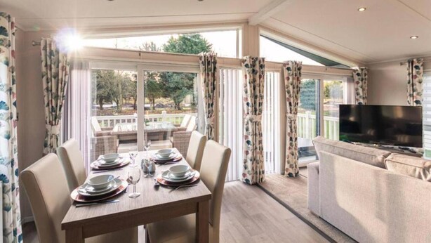 A dining area with a table set for four, a sofa, and a TV. - Host Stay Woodland Jewel Lodge (York)