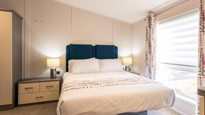 A hotel room with a bed, two bedside lamps, a nightstand, a wardrobe, and a window with curtains. - Host Stay Woodland Jewel Lodge (York)
