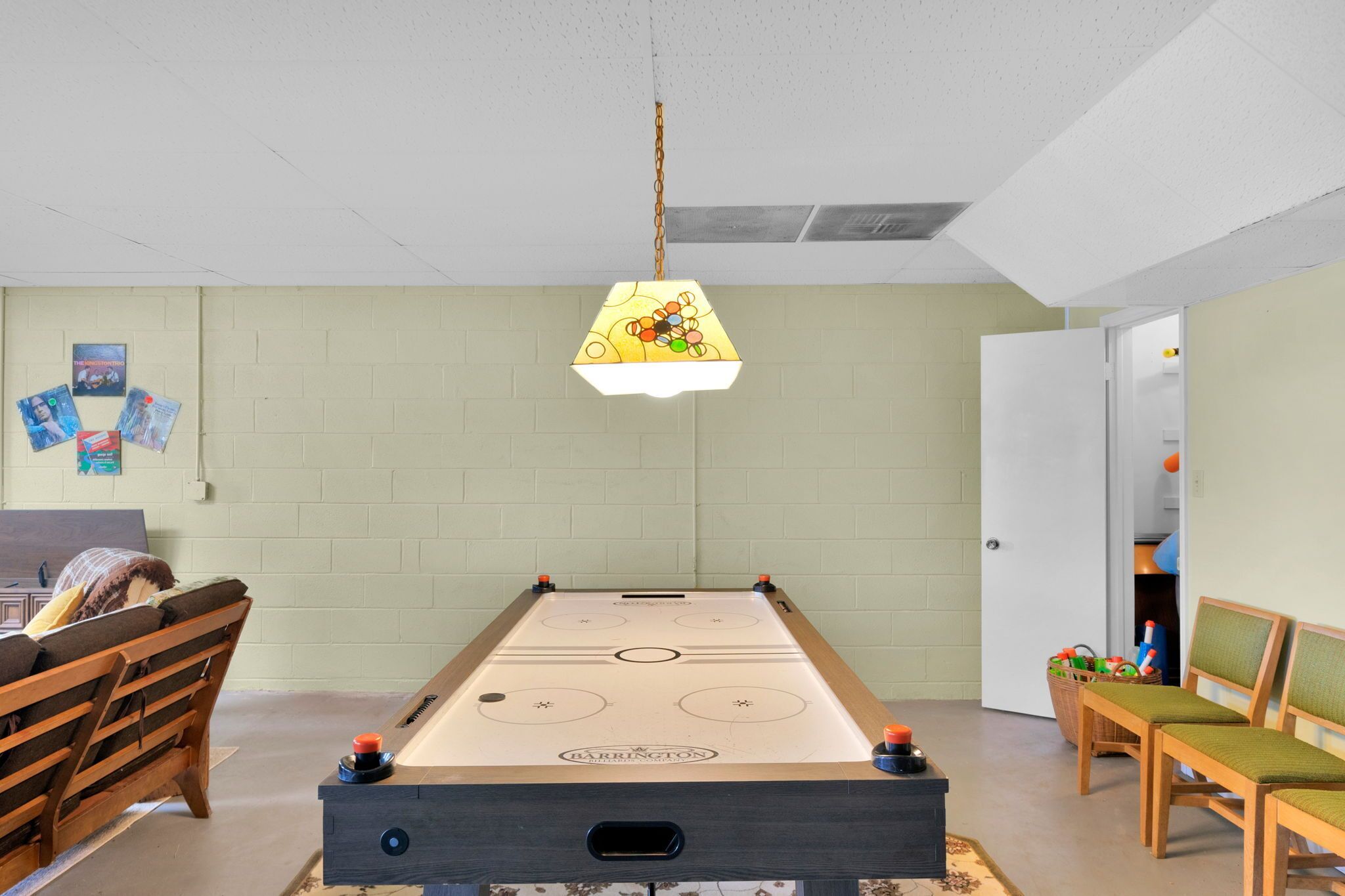 A pool table with a hanging lamp, a wooden bench, and a door leading to another room.