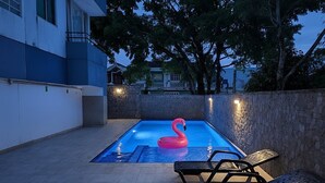Une piscine avec un flotteur en forme de flamant rose, des chaises longues et un mur en pierre.