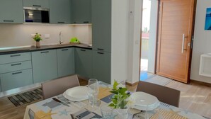 Een moderne keuken met grijze kastjes, een ingebouwde oven, en een eethoek met een tafel gedekt voor twee personen.