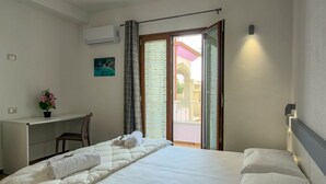 Een hotelkamer met een bed, een bureau, een stoel en uitzicht door een glazen deur.