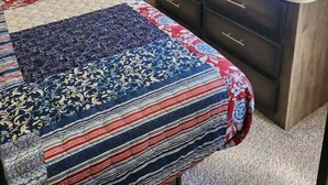 Un dormitorio con cama, televisor, cómoda y ventana.
