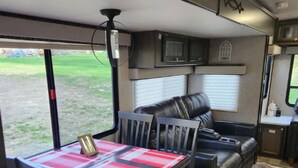 Interior acogedor de una autocaravana con mesa de comedor, sillas, sofá y zona de cocina.